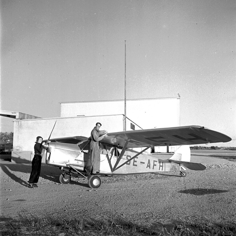 Det nygifta paret Nils och Brigit Thüring med sin Puss Moth SE-AFH vid norra kortsidan av hangar A på Bromma 1939.